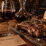 Vin rouge corsé : bouteille, verre et côte de bœuf pour accords tanins